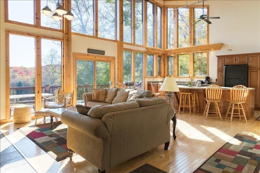 Living room and dining room with large doors leading onto deck with a view over the woods.