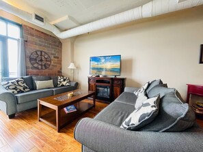 Stylish Industrial Living Room
Exposed brick, plush sofas, and a warm fireplace create a cozy atmosphere in this modern-industrial loft. Kick back, watch a movie, or enjoy a relaxing evening with stunning lake views.
