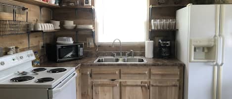 Kitchen with stove, refrigerator, microwave, coffee pot, pots/pans, dishes