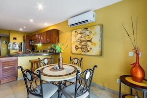The large common area has a couch, a small dining table, and the kitchen in the background