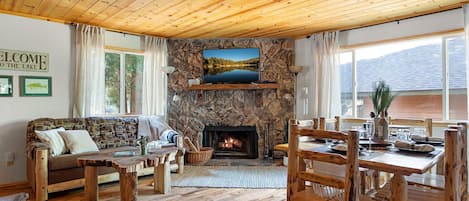 Open living area with stone fireplace, oak floors, pine ceiling, & log furniture