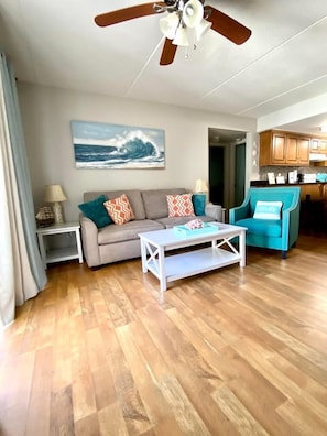 Living room with fold out couch and balcony that overlooks the courtyard pool.