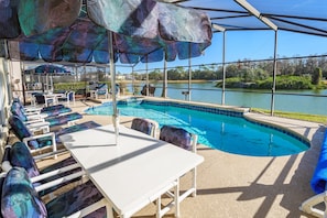 there are 2 tables and several chairs and loungers on the pool deck