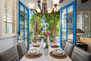Dine in style with this elegant indoor/outdoor setup—blue French doors to patio