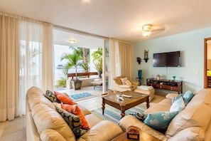 The living room has two comfortable couches and a 55 inch flat screen TV with lots of English channels