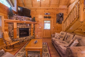 Living room with stone fireplace, 60" Flat screen TV with DVR and internet.