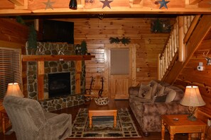 Living room with stone fireplace, 60" Flat screen TV with DVR and internet.