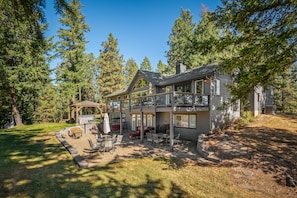 Full view of the rear of the property with wooded views and grass area