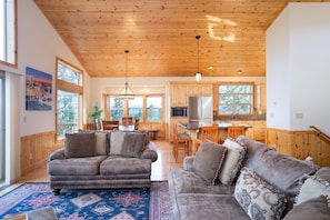 Living, Dining, Kitchen Area (Upper Level) - Easily access the living, dining and kitchen area from the open grand floor plan. The cathedral ceiling and wall of windows throughout this grand room provides incredible views and natural light! A spacious open deck off the living room invites you see the beauty that Tahoe Donner has to offer!