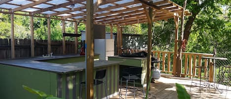  Outdoor kitchen has sink refrigerator ,microwave , bar seating, griddle