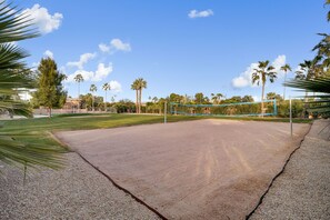 Private sandy volleyball court surrounded by lush grounds and palm trees.