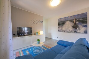 Wohnzimmer mit Schlafsofa, Smart-TV und Zugang zum Balkon