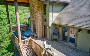 Expansive back deck with fireplace and hot tub next to each other.
