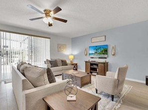 Cozy living room with natural light, plush seating, and a ceiling fan for comfort.