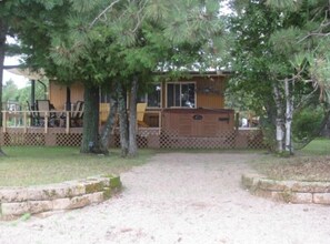 The deck off of the cabin with a hot tub, BBQ gas grill and a shaded eating area