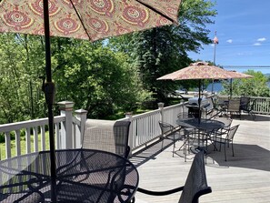 Deck with tables, seating, umbrellas and two gas grills with view of Lake George