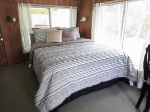 Comfy Queen bed is nestled next to the windows offering views of nature