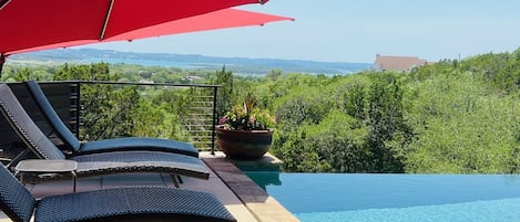 Umbrellas open and shading the loungers by the pool. 