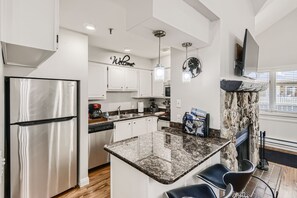 A full modern kitchen with bar stools and all stainless steel appliances