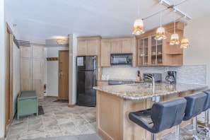 Kitchen - Granite counters with seating, pendant lighting, and full size appliances.