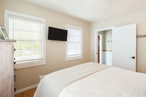 Queen bed with TV, dresser, and plenty of light. - Comfortable queen bed in the first bedroom.