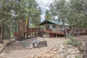 Front/side view of cabin, tree house and fire pit area.