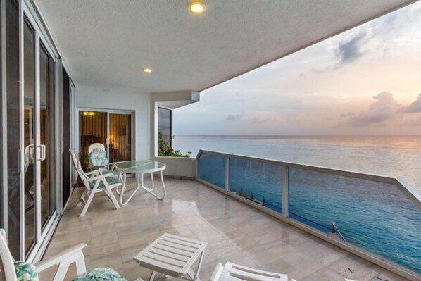 A large oceanfront balcony has plenty of seating for lounging and dining