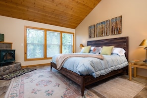 Master bedroom upstairs with view of woods and propane stove.