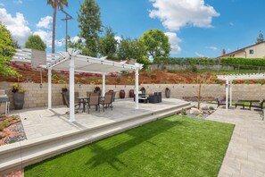 Backyard with fountains, artificial grass, shaded patio, and plenty of seating