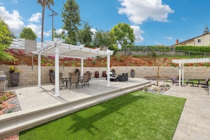 Backyard with fountains, artificial grass, shaded patio, and plenty of seating