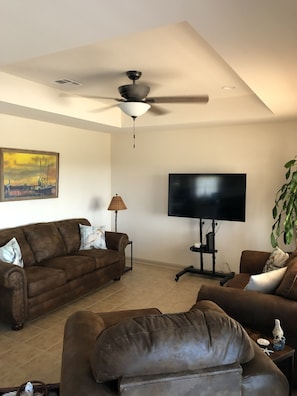 Living room area with sofa, loveseat, chair and ottoman with large screen TV