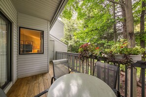 A balcony with a table and chairs, providing a charming spot to enjoy the garden view.
