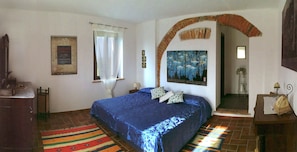 Wide view of the bedroom with the king size bed and the antique furniture