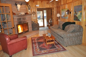 Warm & cozy living room w/ massive stone fireplace, hardwood floor & hide-a-bed