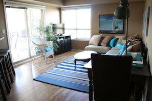 Living room with desk area and TV.  Sliding doors leading to balcony.