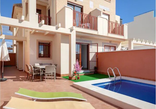 The front view of the villa with private swimming pool, seating area + loungers