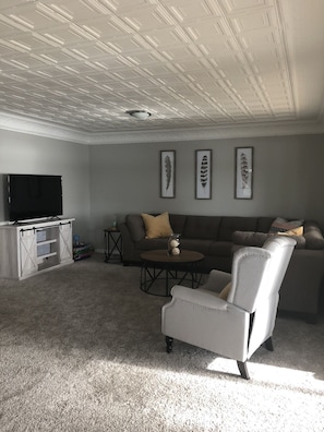 Living room with sectional couch and big screen smart TV with Netflix and Hulu. 