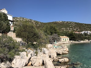 House on left, beach with chaise lounges & umbrella on right center of photo