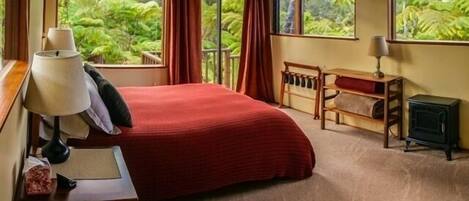 Spacious bedroom with several large picture windows and comfortable queen bed.