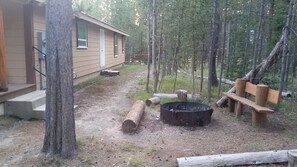 Fire pit with roasting hot dog
 sticks, firewood, poker and shovel on shed wall.