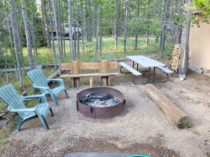 Fire pit with cut wood and a picnic table.