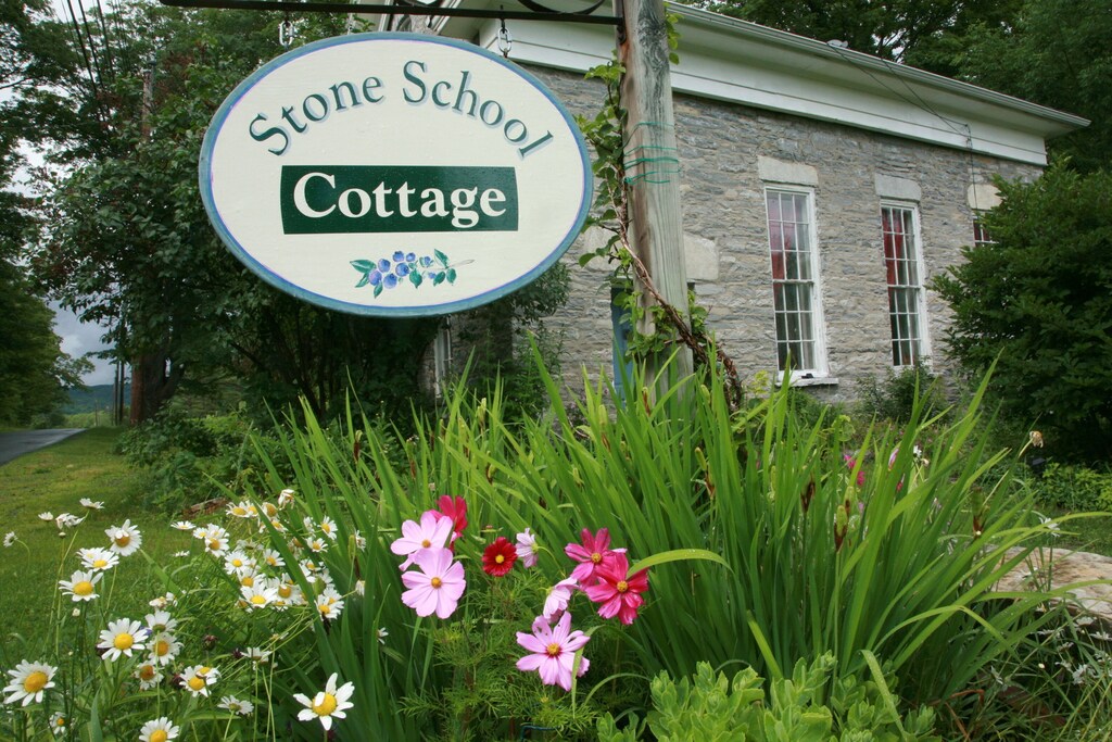Exterior of cabin, sign reads: "Stone School Cottage"