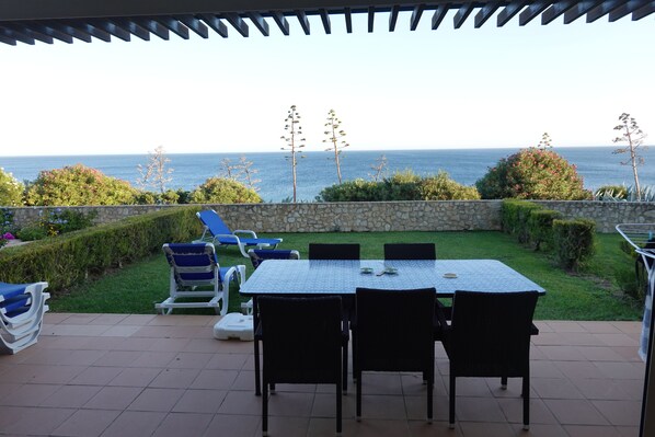 THE VIEW!  Outdoor dining table on patio with loungers on lawn.