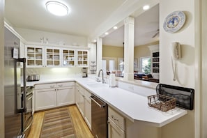 Fully equipped kitchen that looks into an open and spacious sitting room.