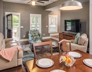 There is a sofa and 2 sofa chairs in the main living room with a TV.