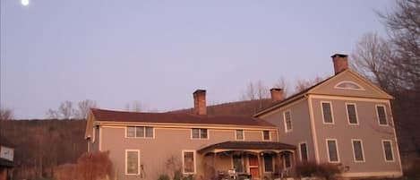 Sunrise lights up the front of the house. Moon sets over the mountain.