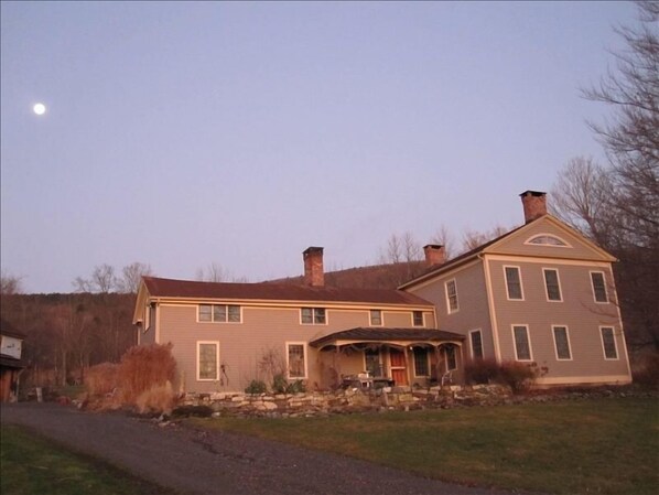 Sunrise lights up the front of the house. Moon sets over the mountain.