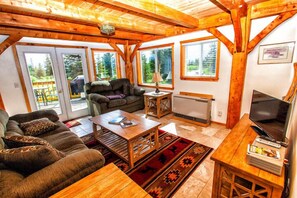 Living room opens to deck area with BBQ and wrought iron patio set.