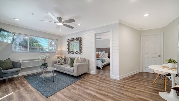 The cozy bedroom in the background offers a peaceful retreat with plush décor