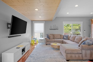 Living room includes cedar-paneled accent ceiling and 60-inch television 